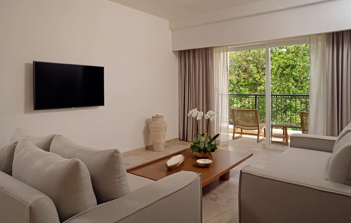 Hacienda Tres Rios hotel suite with living area, balcony view, and natural light.