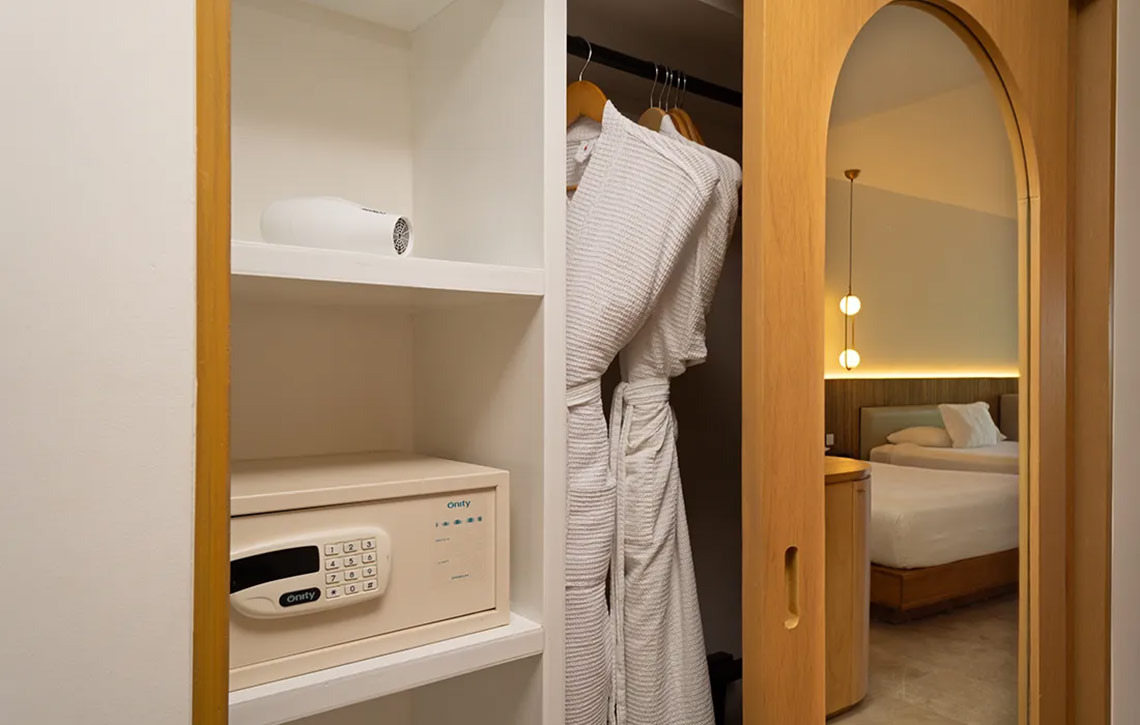 Hotel room closet with safe, hairdryer, and robes, view of beds at Hacienda Tres Rios.