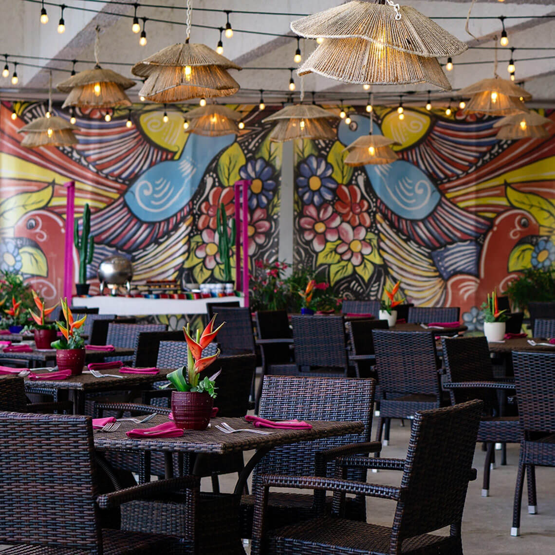 Dining patio with vibrant mural and woven furniture at Sunset Royal Beach Resort.