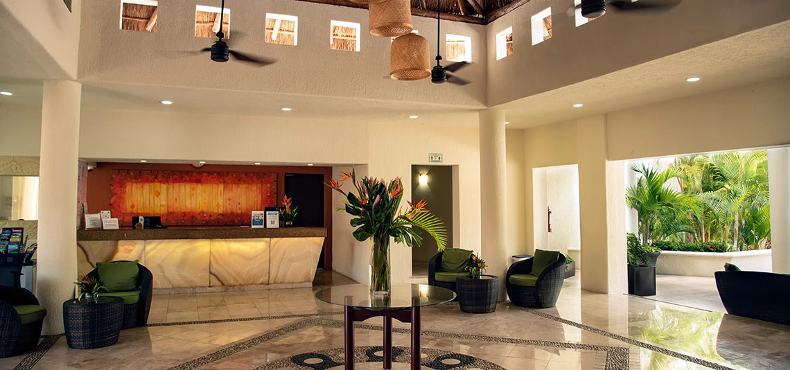 Lobby principal de Laguna Suites | Página Oficial con recepción, sala de estar y vista al jardín.