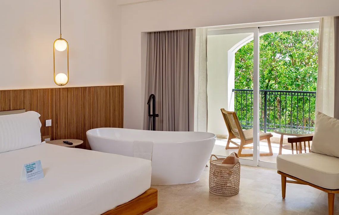 Elegant Hacienda Tres Rios suite featuring a freestanding tub, luxurious bed, and balcony with lush views.