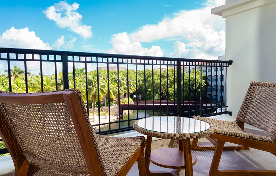 Balcony view at Hacienda Tres Rios Resort: chairs, table, and tropical landscape.