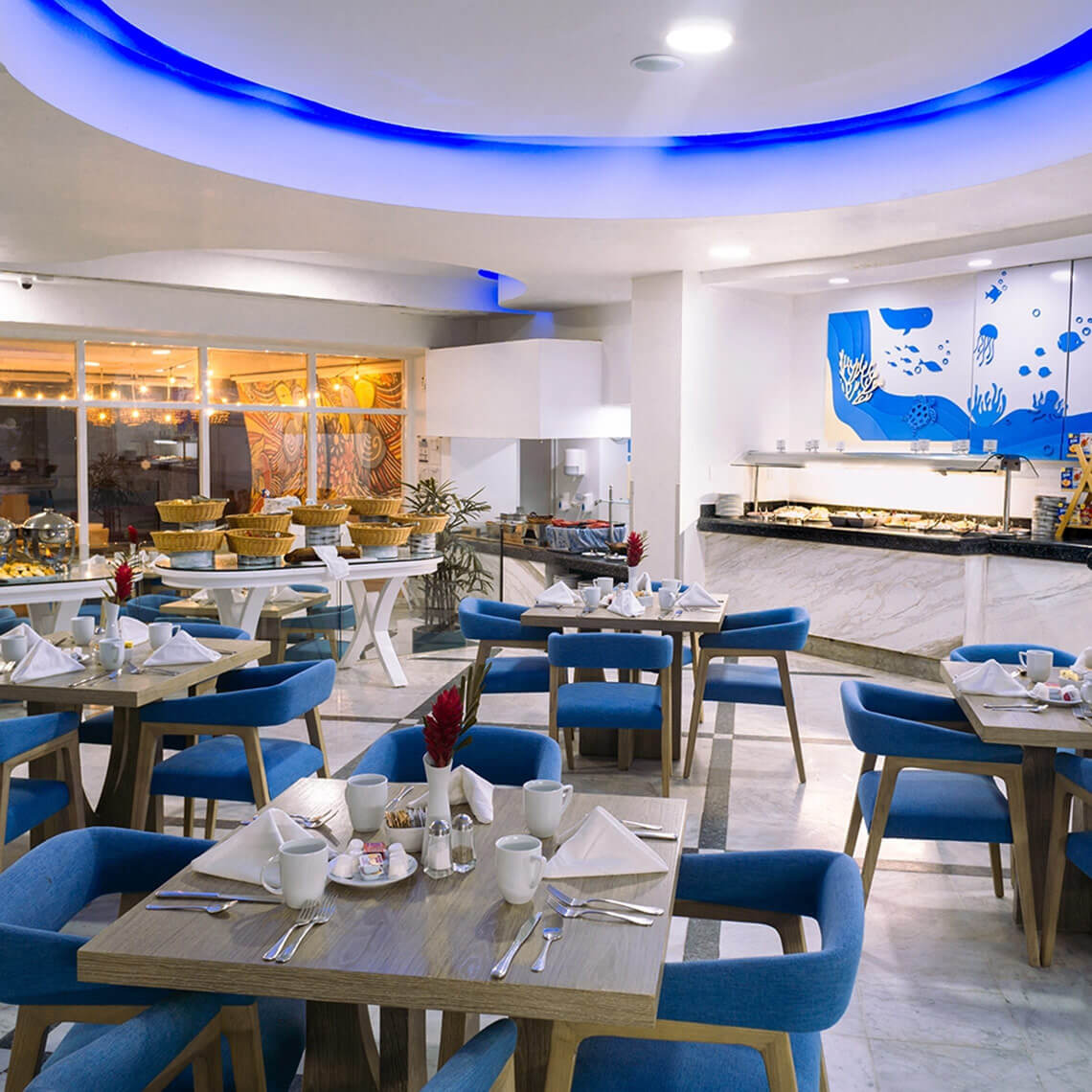 Breakfast buffet at Sunset Royal Beach Resort, featuring elegant dining and blue seating.