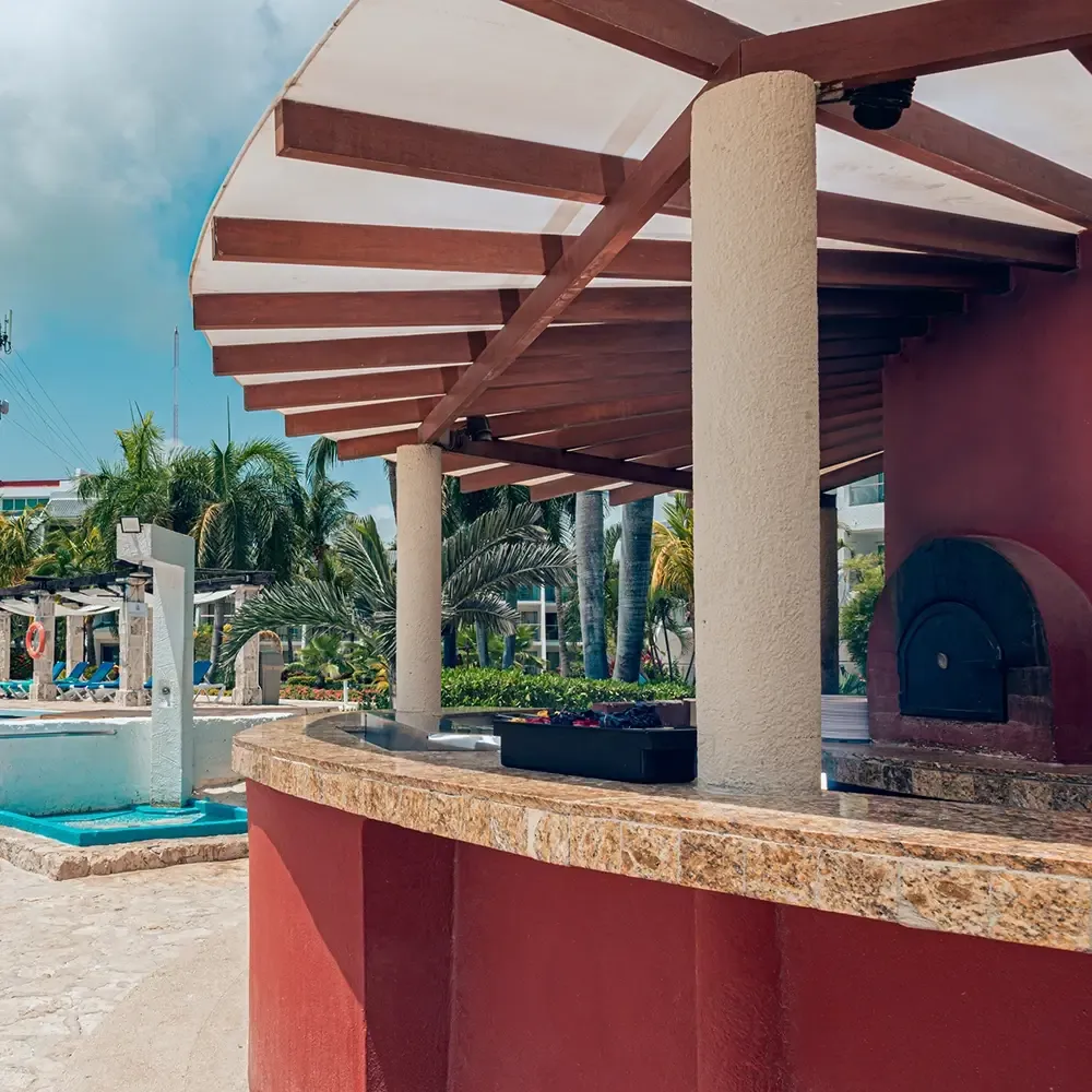 Sunset World Resorts: Corporativa - Outdoor bar and pizza oven by the pool with palm trees.