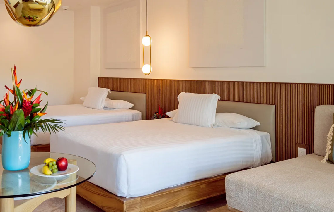 Luxurious Hacienda Tres Rios room with two beds, tropical flowers, and modern decor.