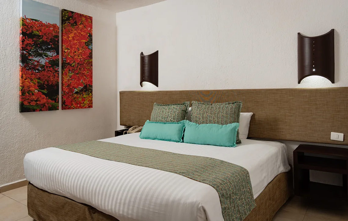 Habitación principal en Laguna Suites con cama king, arte vibrante y luz ambiental acogedora.
