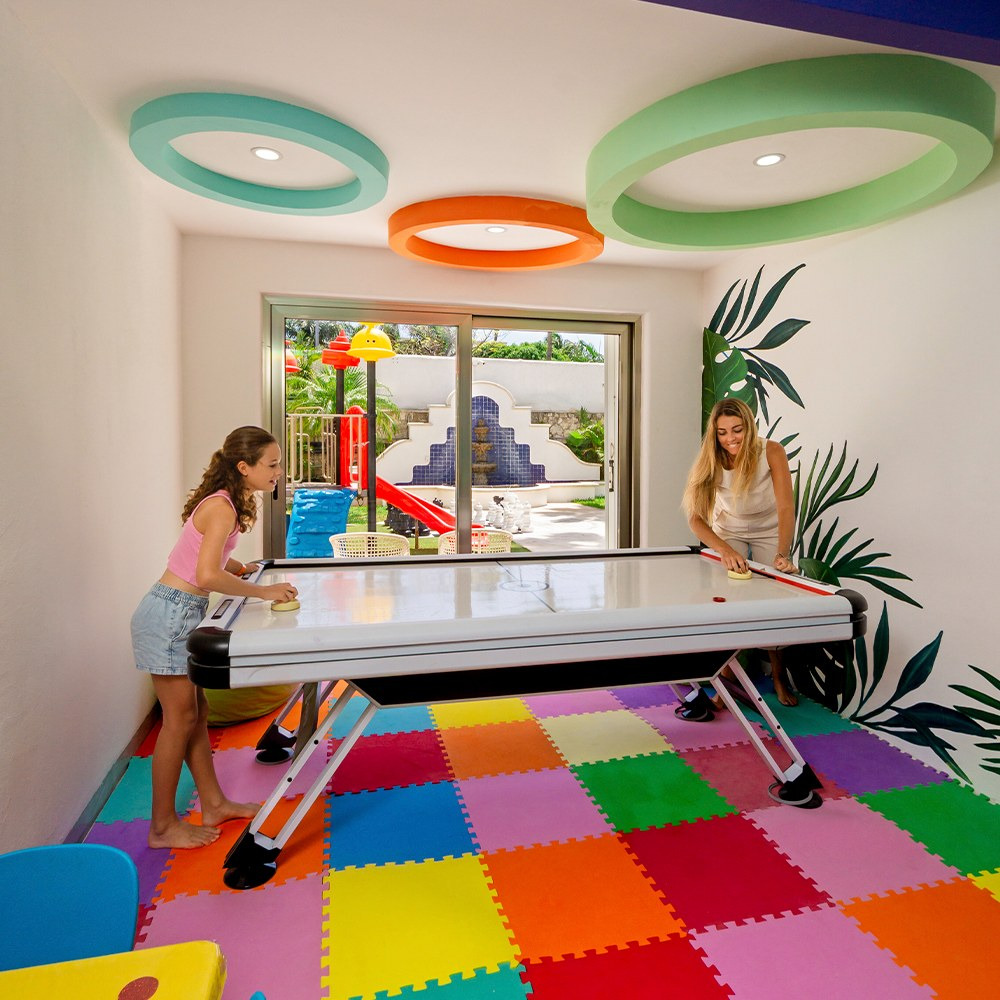 Adultos y niños disfrutan en Sunset World Resorts: Corporativa sala de juegos.