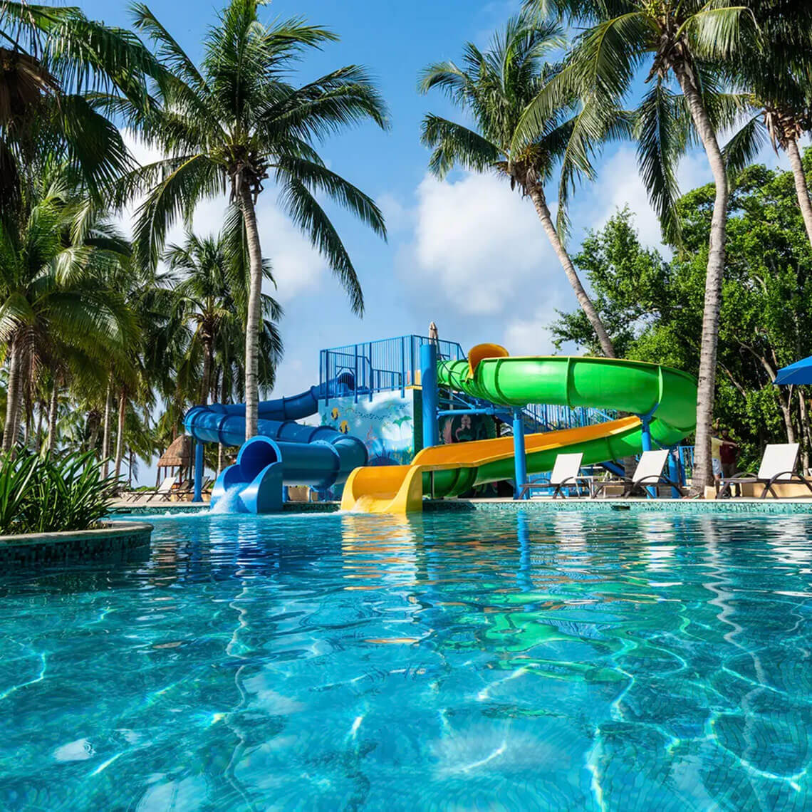 Water slides and pool at Hacienda Tres Rios Resort with palm trees.