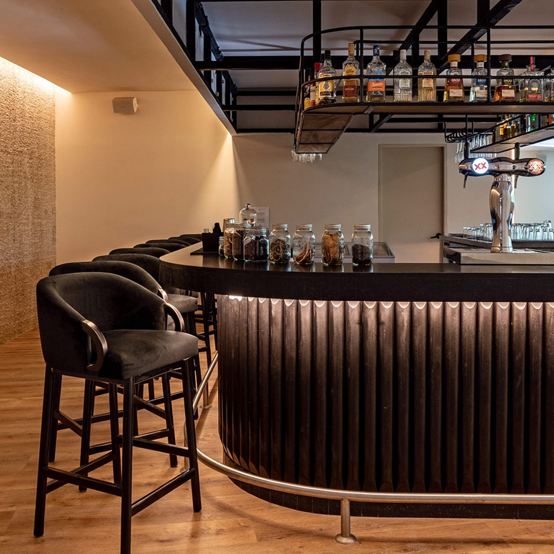 Hacienda Tres Rios bar with bar stools and liquor bottles.