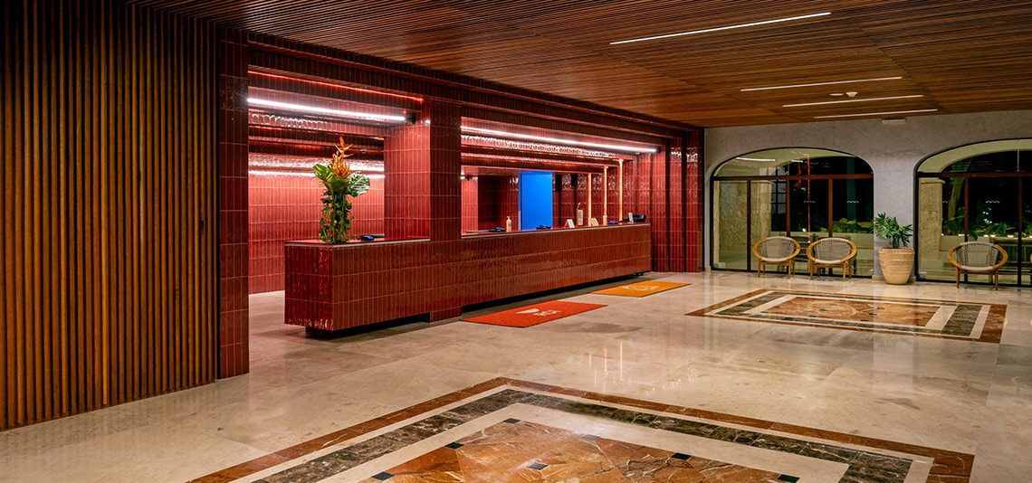 Hacienda Tres Rios hotel lobby: vibrant red reception, wood ceilings, marble floors, elegant seating.