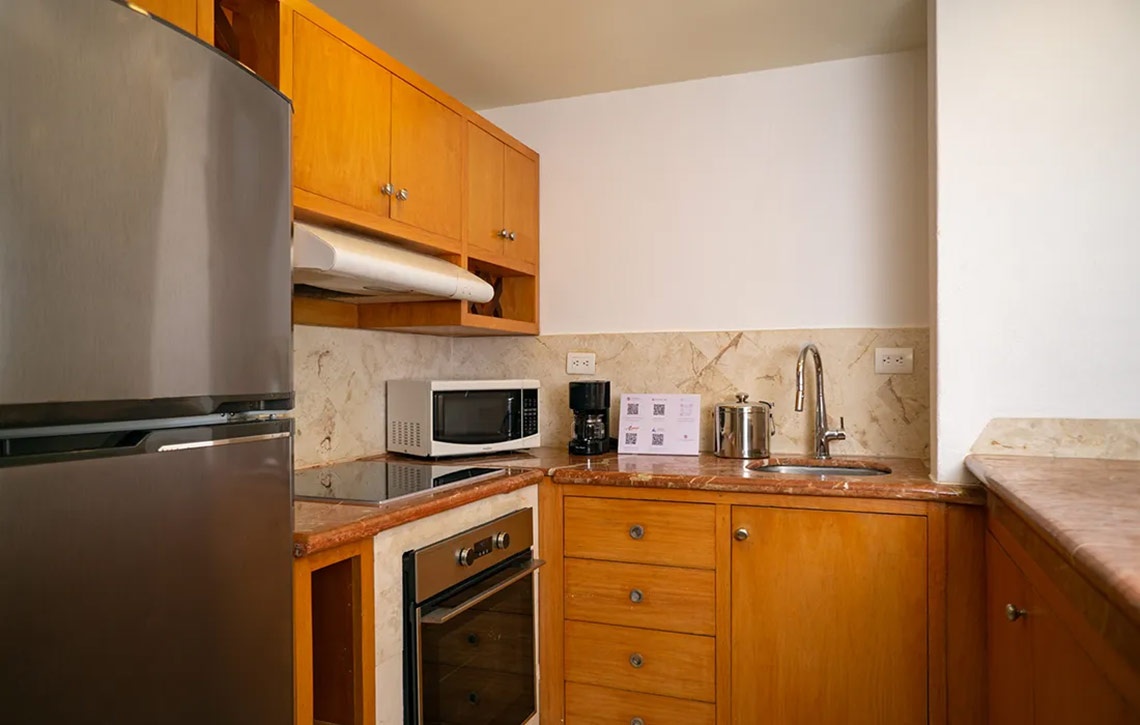 Pequeña cocina de Sunset Fishermen Beach Resort | Página Oficial: refrigerador, microondas, estufa y lavabo.