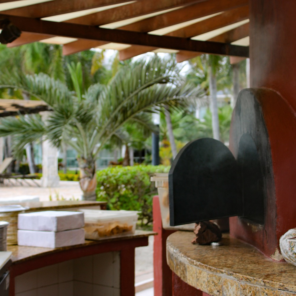 Sunset World Resorts: Corporativa - Outdoor bar and pizza oven by the pool with palm trees.