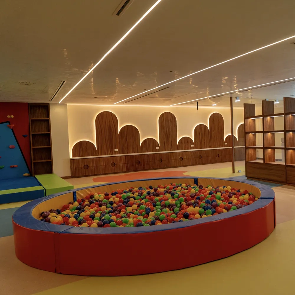 Colorful ball pit Sunset World Resorts: Corporativa in a hotel playroom with climbing wall and shelves.