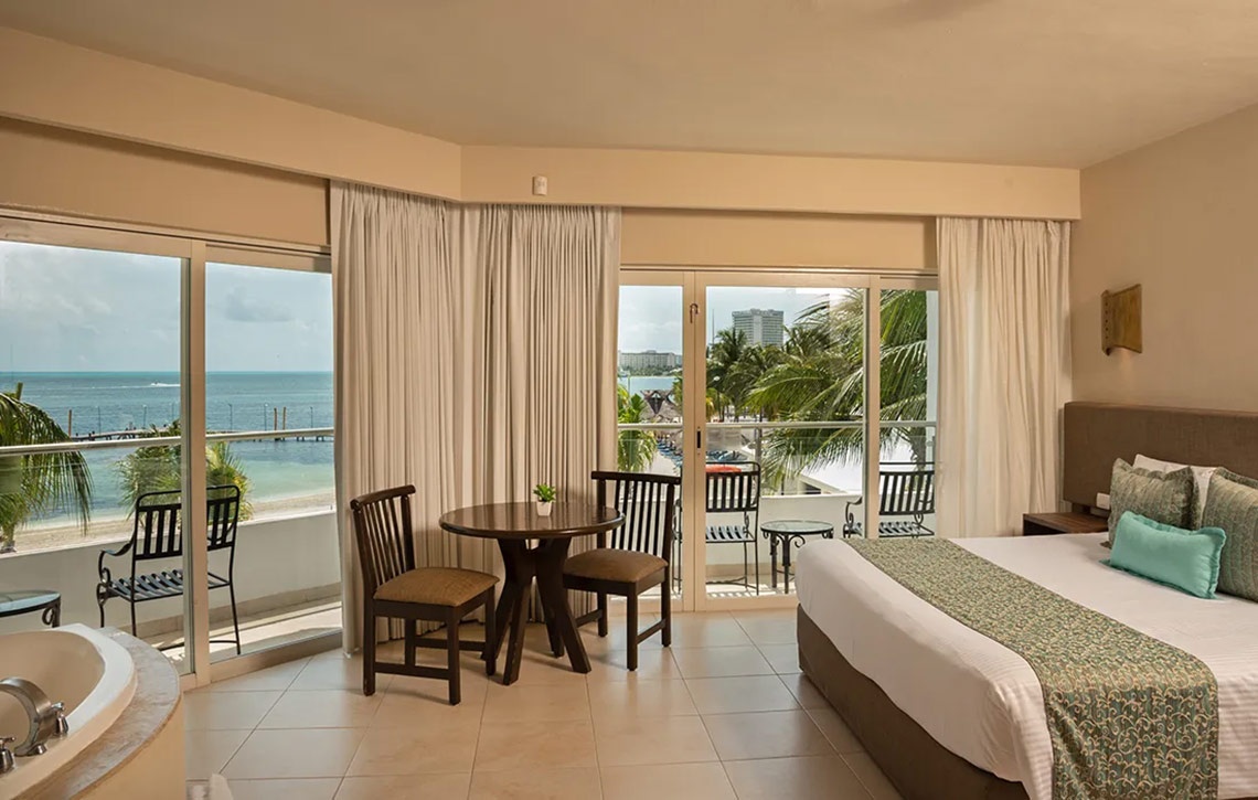 Ocean Spa Hotel room with ocean view balcony, bed, and dining table.