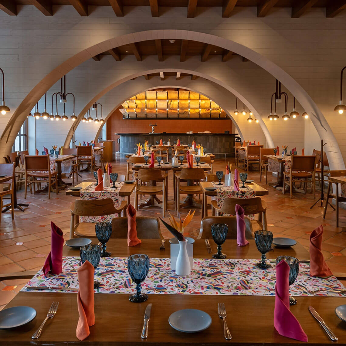 Elegant Hacienda Tres Rios restaurant with arched ceilings, colorful table settings, and a bar.