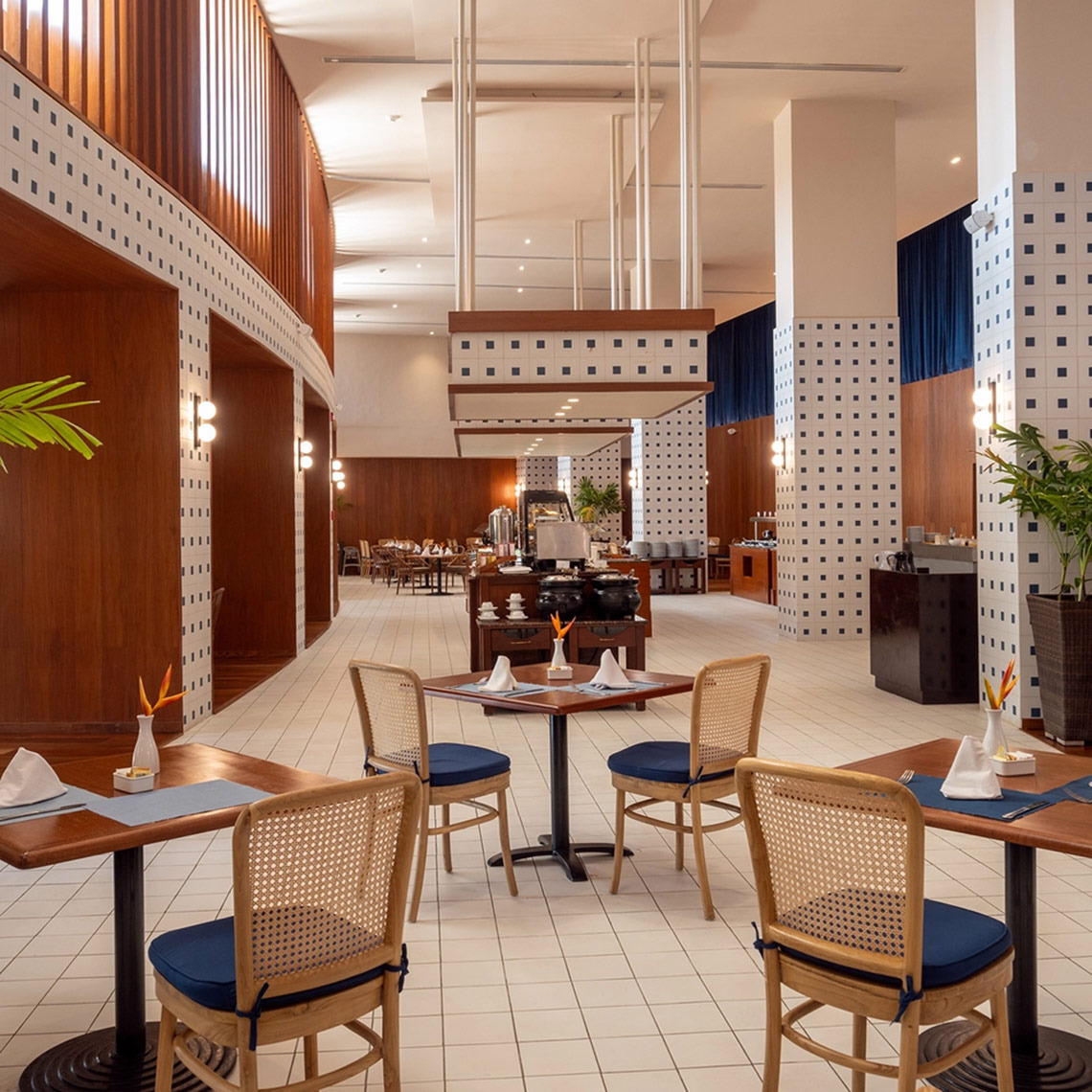 Elegant dining room at Hacienda Tres Rios resort, featuring wood accents and blue-cushioned chairs.