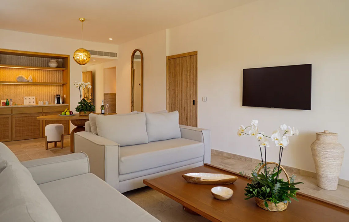 Living room with light grey sofas, coffee table, and orchids at Hacienda Tres Rios.