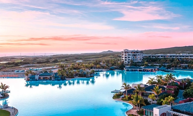 a large swimming pool surrounded by palm trees and buildings