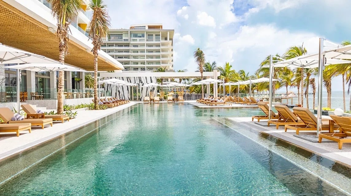 a large swimming pool surrounded by palm trees and buildings