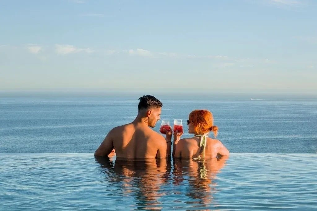 a man and a woman are sitting in a swimming pool holding drinks