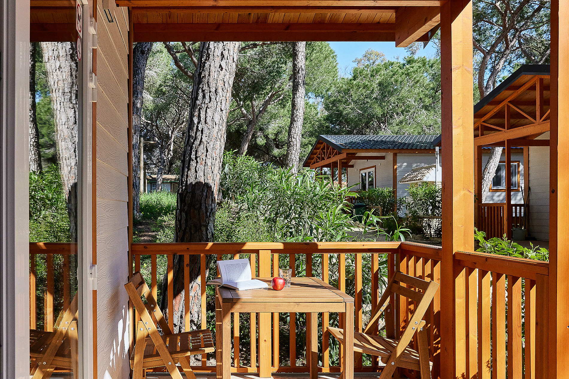 Terraza de bungalow con mesa, sillas, libro y manzana, ideal para Taiga: Puerto Santa Maria.