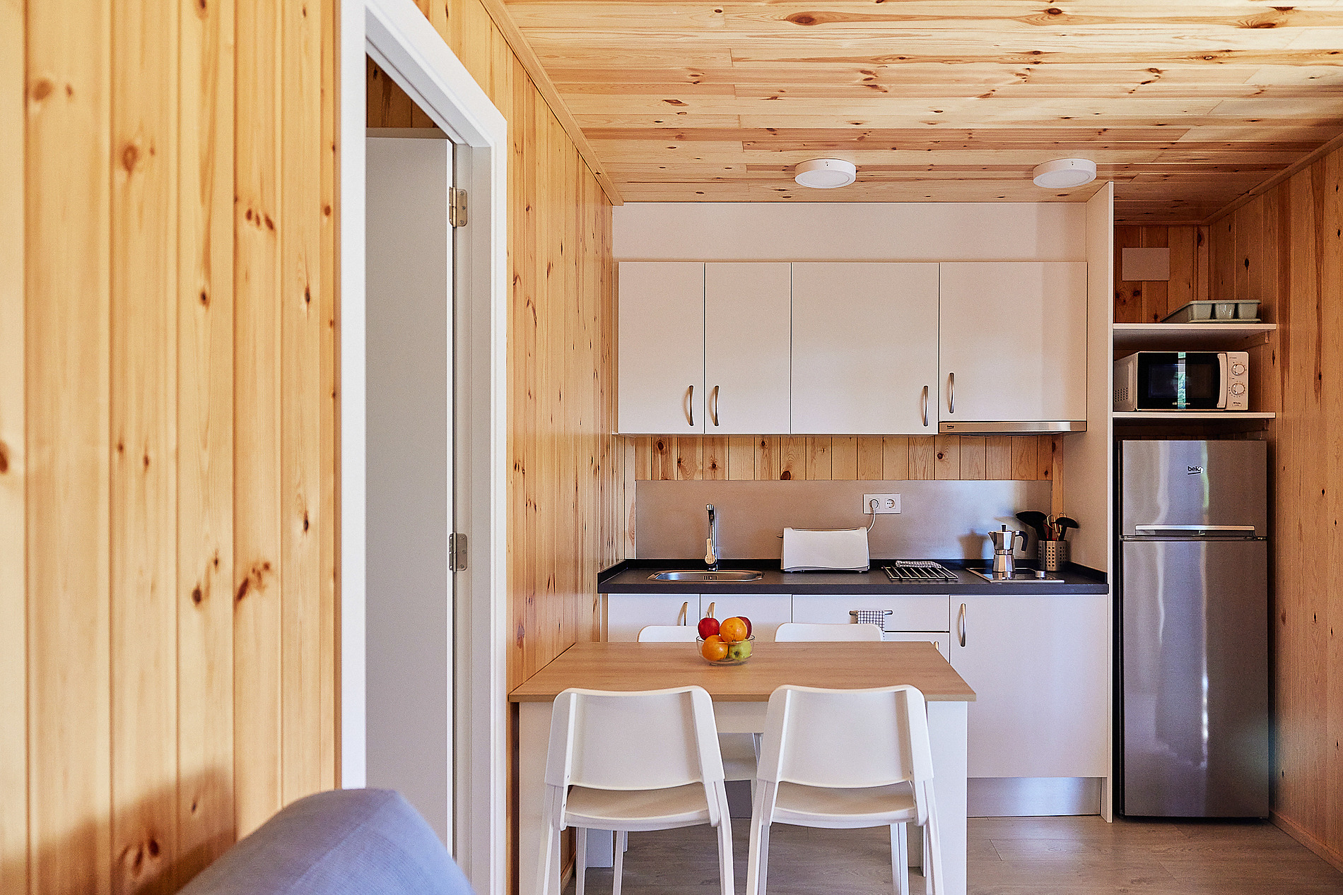 Cocina compacta deTaiga: Puerto Santa Maria con electrodomésticos modernos y mesa para dos.