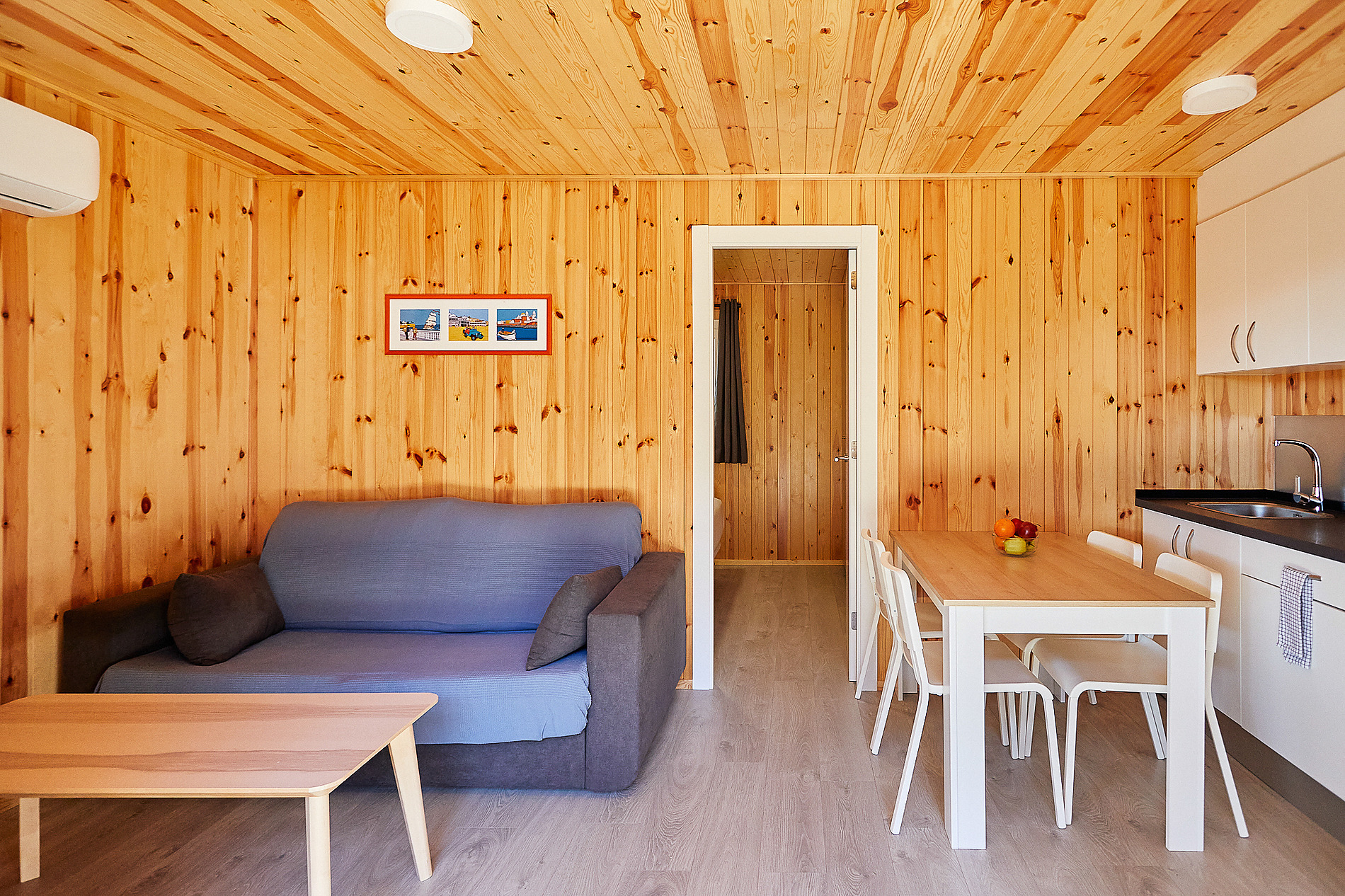 Taiga: Puerto Santa Maria: Habitación con sofá azul, mesa de madera y cocina en hotel acogedor.