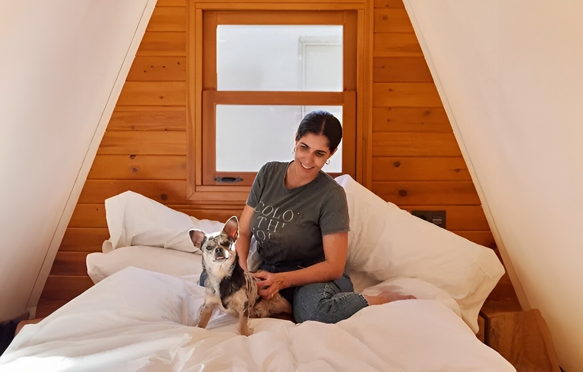 una dona està senta en una cama amb un perro i lleva una camiseta que diu 