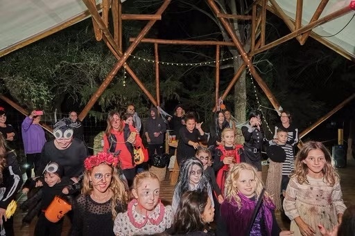 un grup de niños en disfraces de halloween bailan en una carpa .