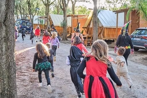 un grup d' adults i nens en costums d' halloween corren per la carretera .