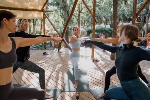 un grup de dones està practicant yoga en una terrassa de fusta .
