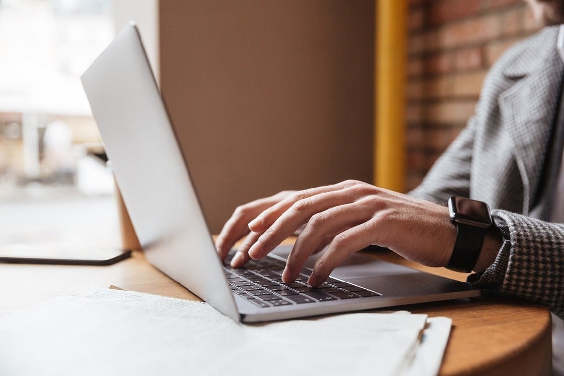 a woman sits in a white chair using a laptop