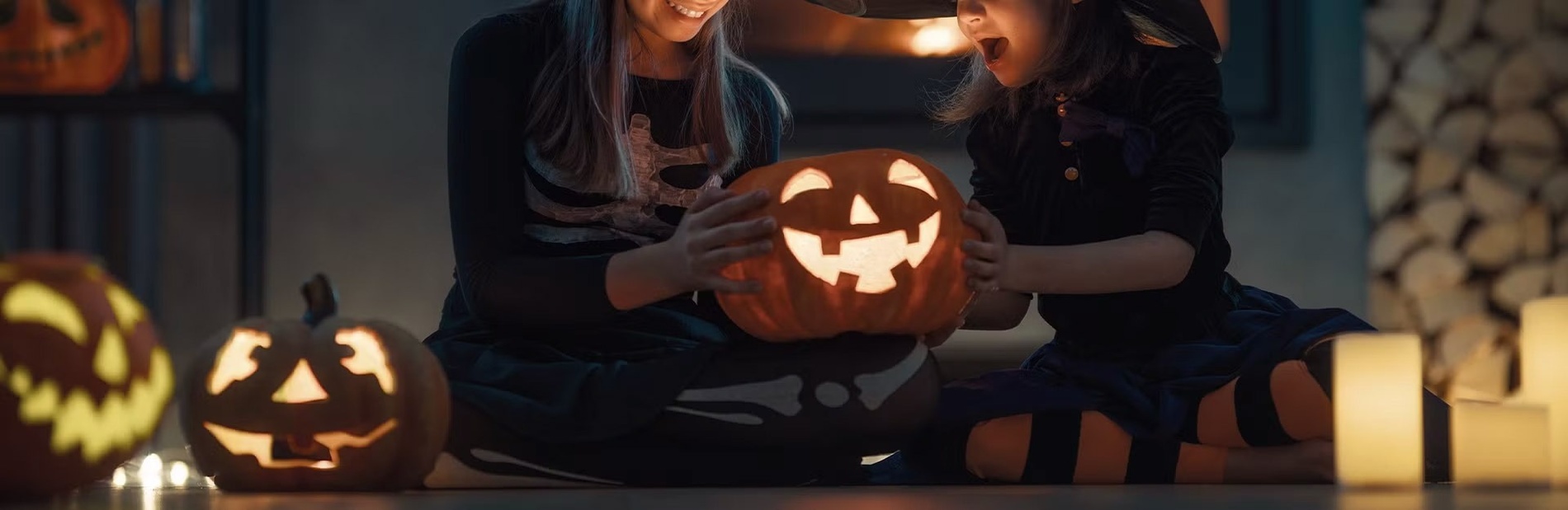 a woman and child are sitting on the floor holding a carved pumpkin