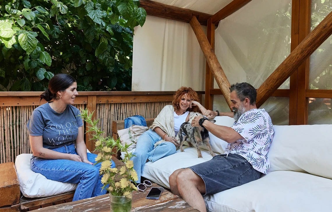 un home i dues dones s'hi senten en un sofà amb un perro