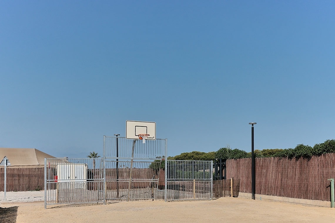 a basketball hoop is behind a fence with a blue sky in the background