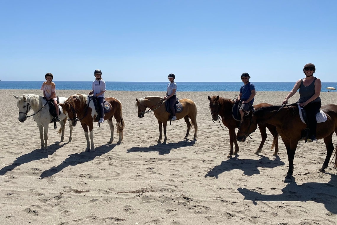 a group of people are riding horses on the beach