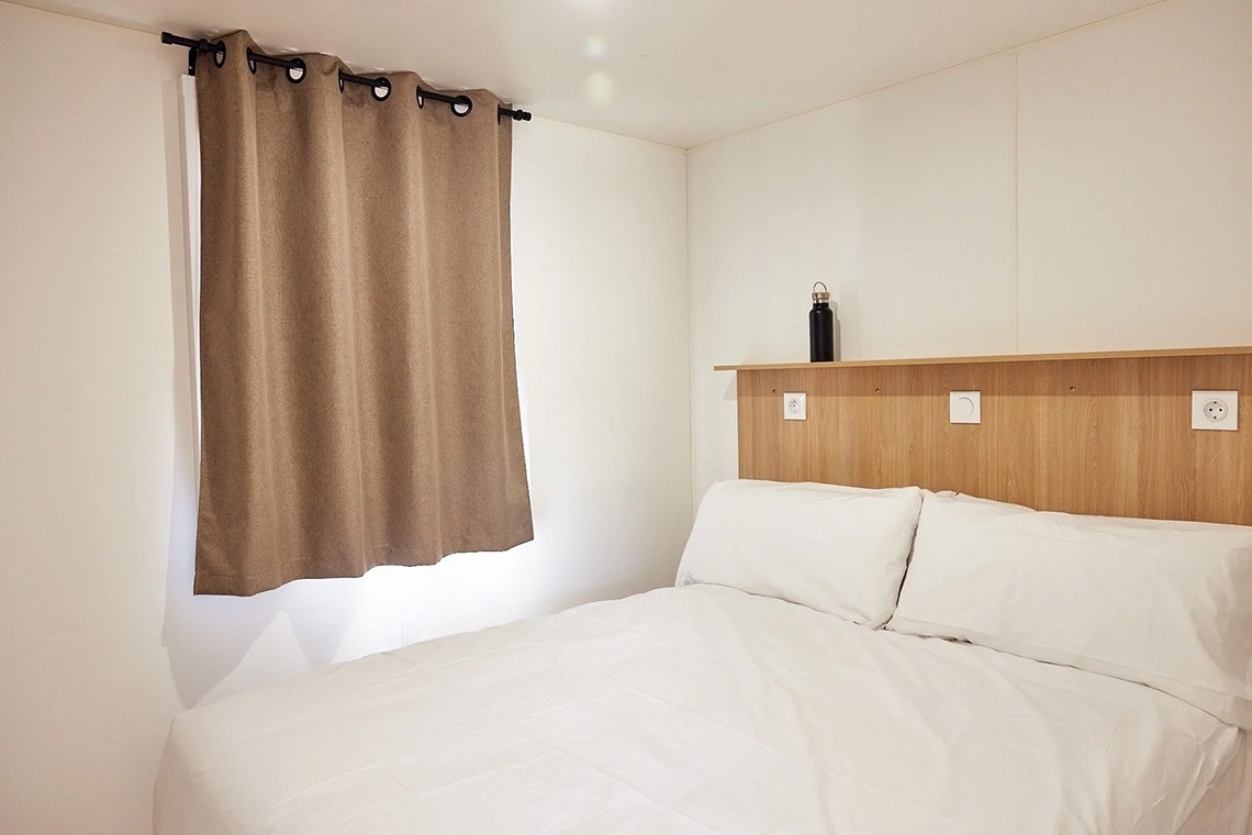 a bedroom with a bed and a window with brown curtains