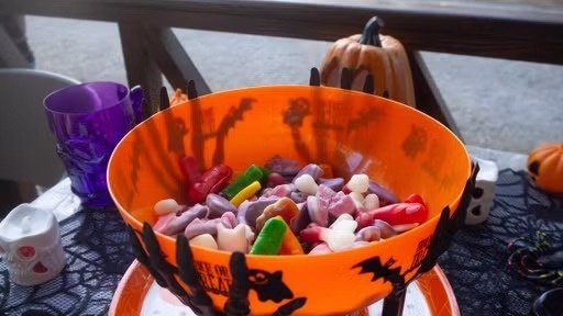 un grup d' niños disfraçats de halloween están a una mesa con calabazas y dulces .