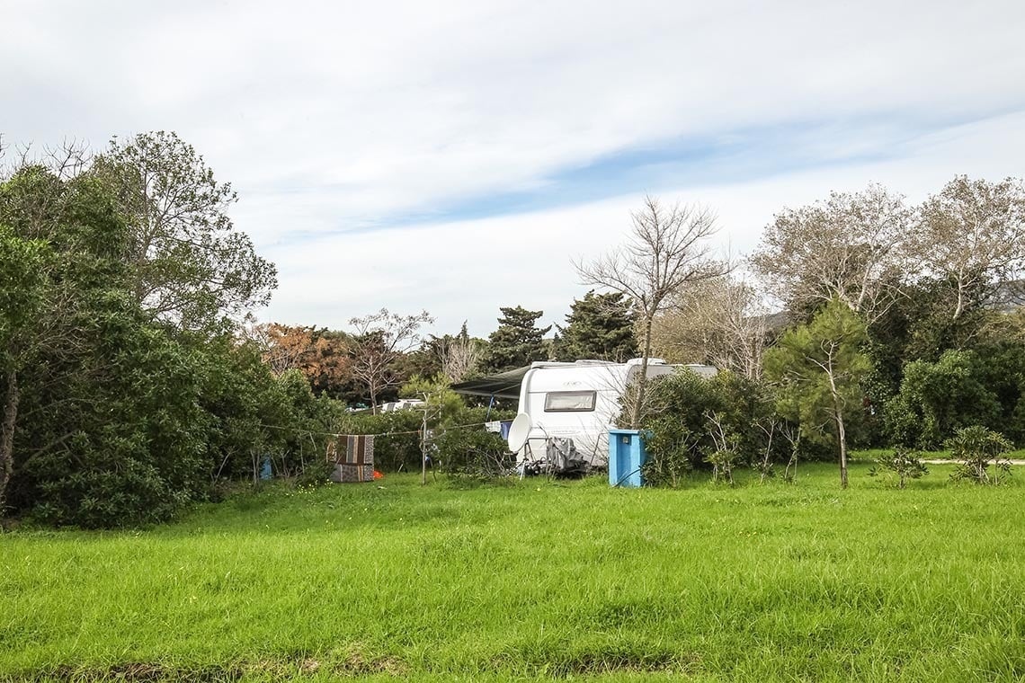 a white trailer is parked in the middle of a grassy field