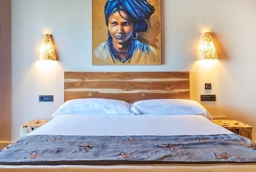 una cama con una pintura de una mujer en la pared