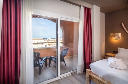 una habitación con una cama y una ventana con cortinas rojas