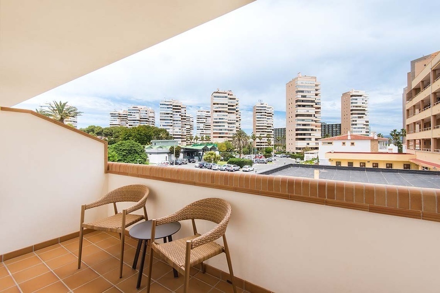 dos sillas y una mesa en un balcón con edificios en el fondo