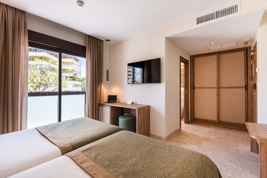 una habitación con dos camas y una televisión en la pared