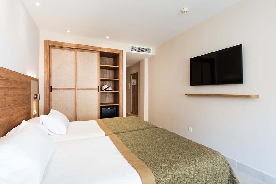 una habitación con dos camas y una televisión en la pared