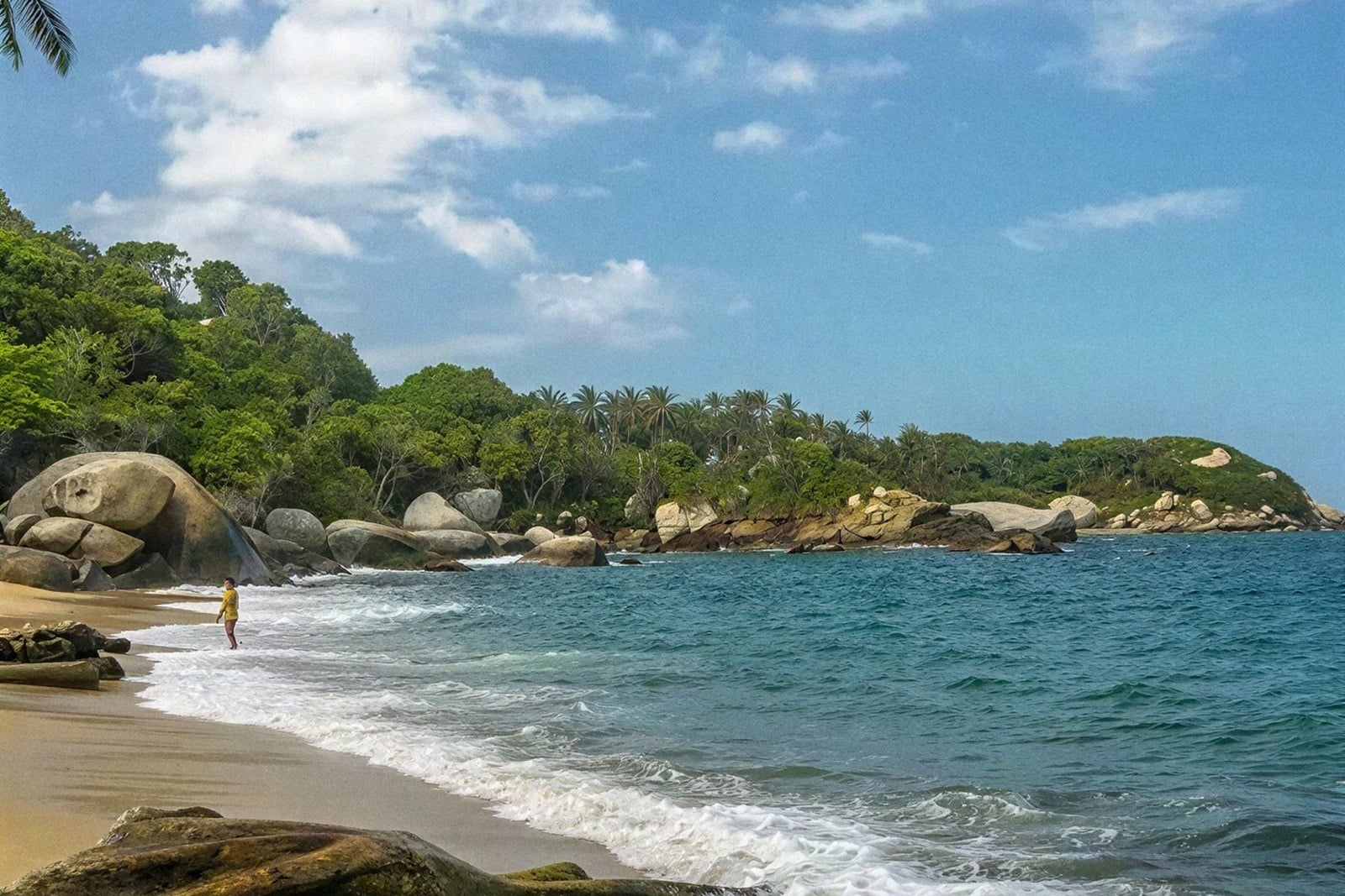 Playa paradisíaca con persona y rocas, ideal para una estancia Tequendama: Corporativa.