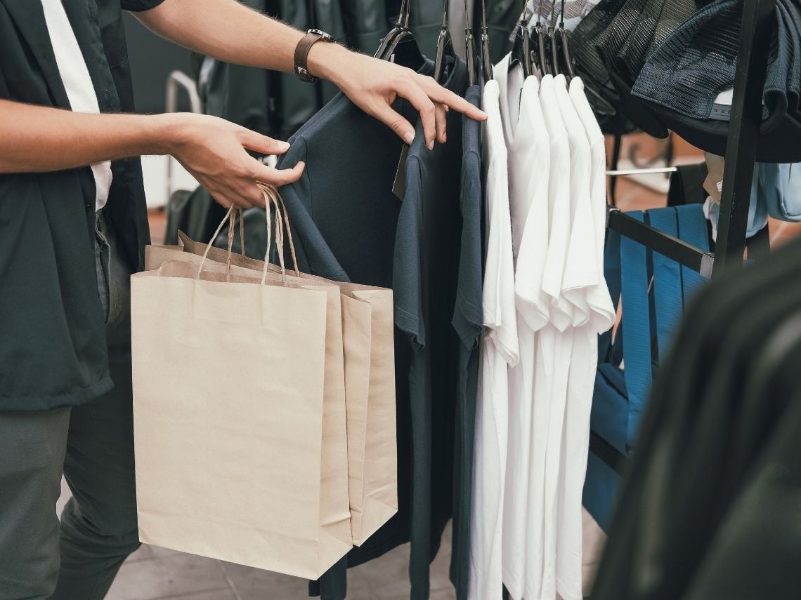 Tequendama: Corporativa - Cliente con bolsas comprando ropa en tienda.