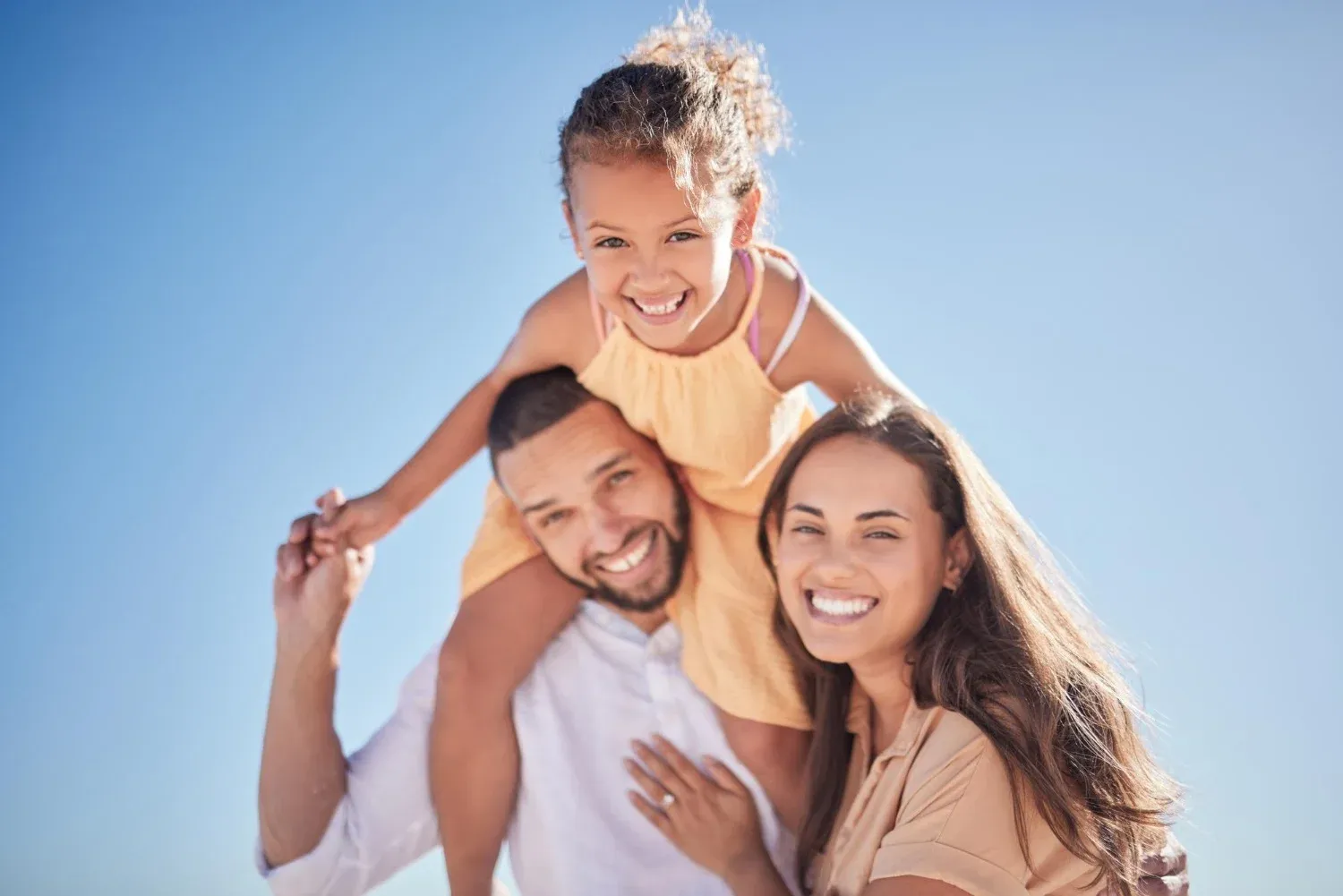 Familia feliz en la playa, hija en hombros de papá. Ideal para tu Tequendama: Corporativa.