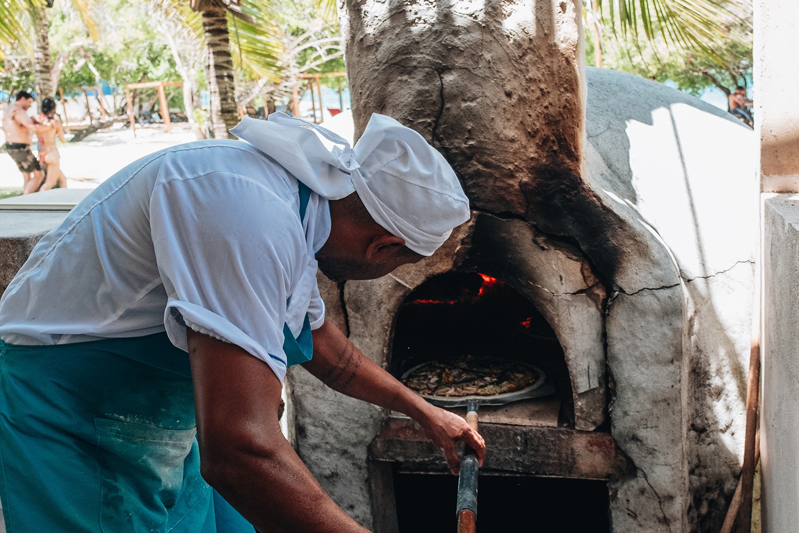 Chef in Tequendama: Corporativa attire cooks pizza in a traditional oven.