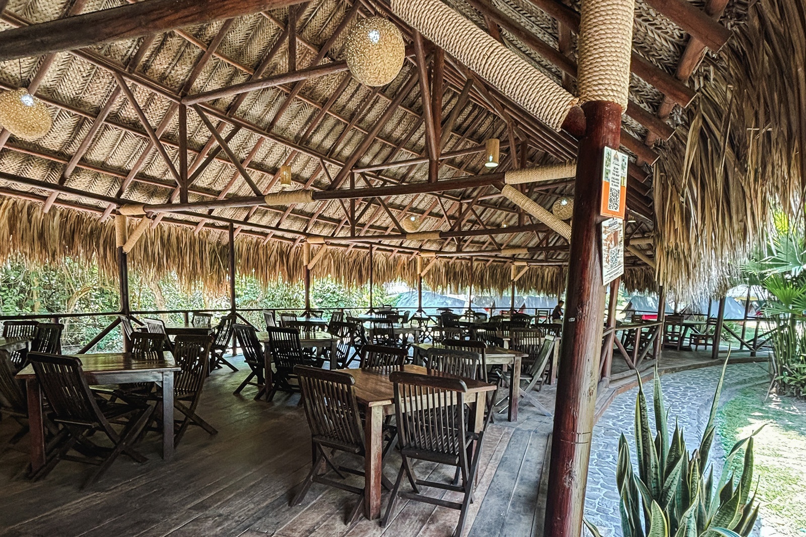 Salón de eventos Tequendama: Mesas de madera bajo techo de palma, ideal para eventos corporativos.