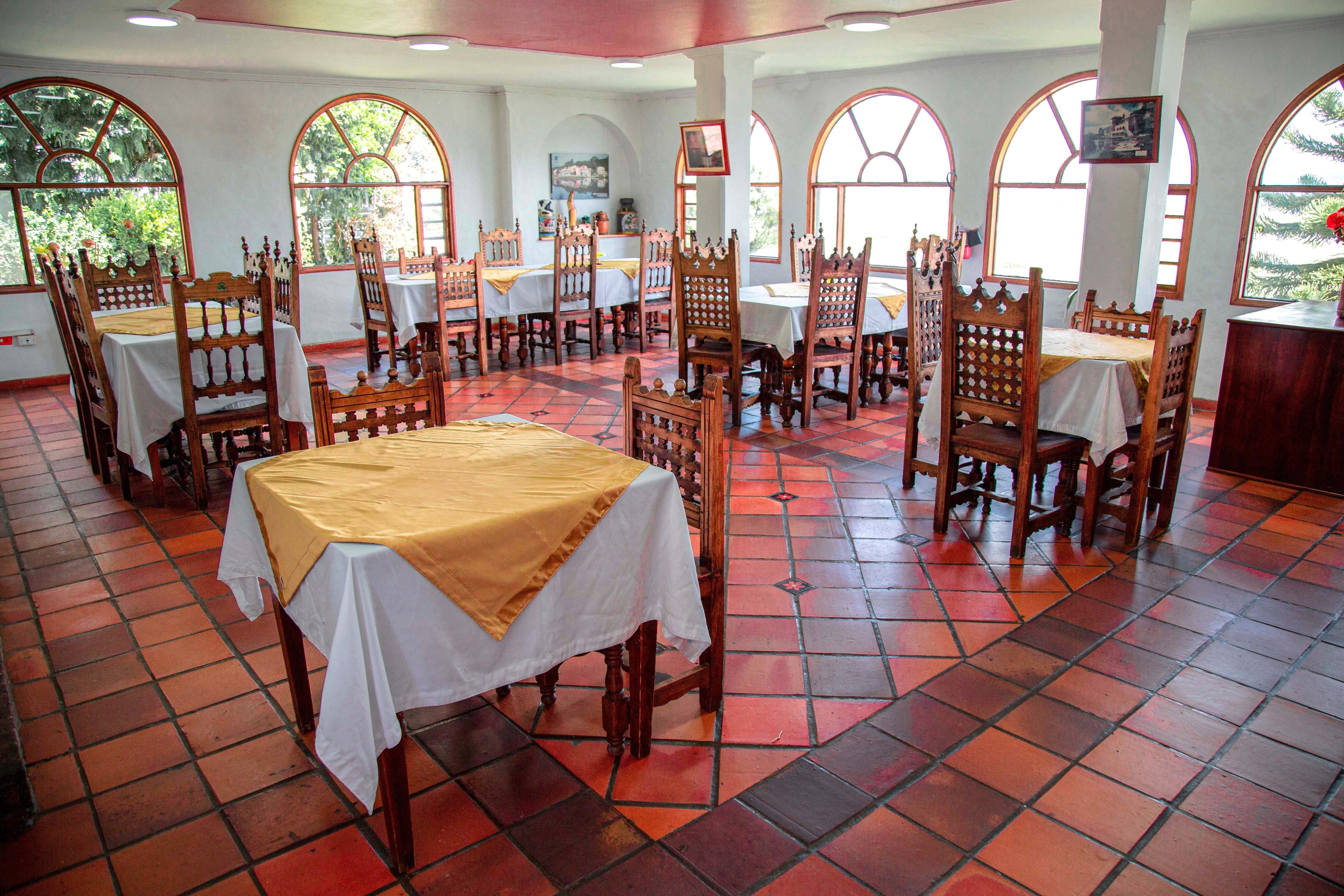 Tequendama Restaurant: set tables, wooden chairs, green views.
